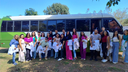 Professora e alunos na frente do ônibus institucional.